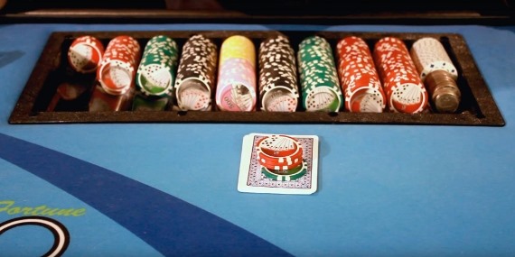 The dealer places the wager on top of their cards. The dealer places the wager on top of their cards.