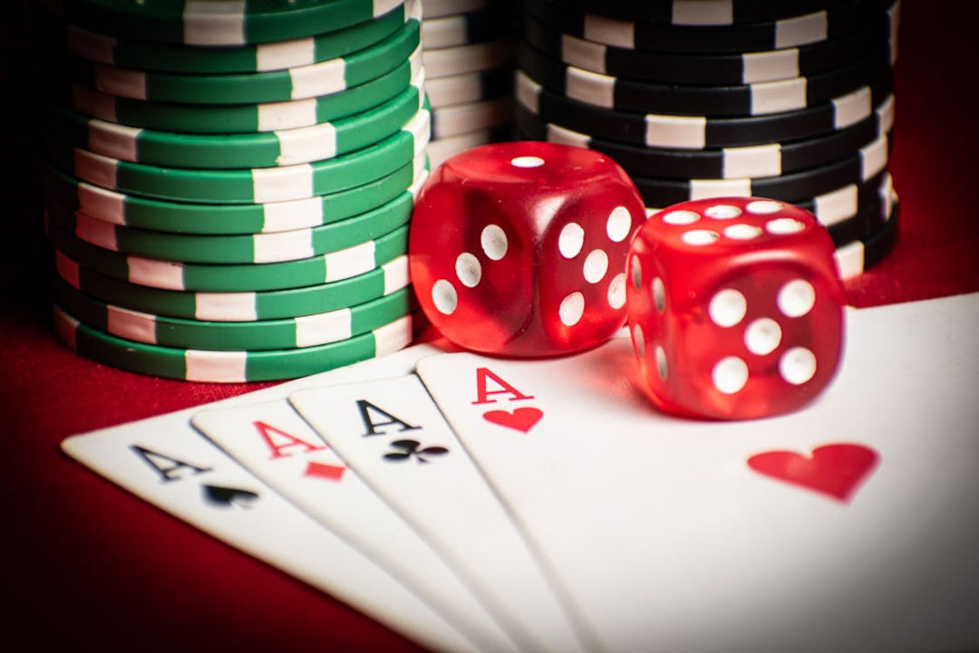 four playing cards with aces on them, dice, and casino chips