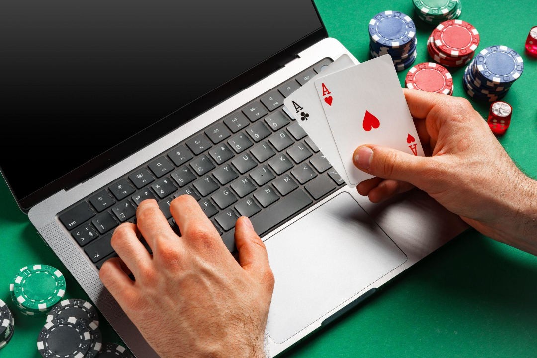 the player is holding a pair of aces in front of a laptop